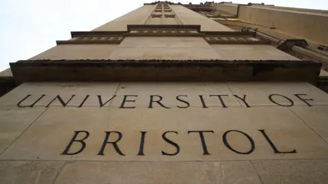 Getty Images A shot pointing up the height of a University of Bristol building. 'The University of Bristol' can be seen spelled out in the beige stone of the building's wall which reaches up to the sky.