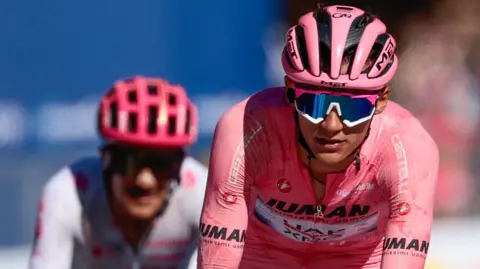 Isaac del Toro (right) crosses the line in the Giro d'Italia leader's pink jersey ahead of nearest rival Richard Carapaz (left)