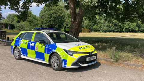 A view of a police car in a park.