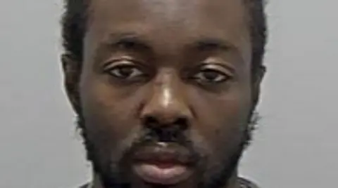 Bedfordshire Police Tyreese Kamau: A man with black hair and a black beard wearing a grey,round-necked t-shirt