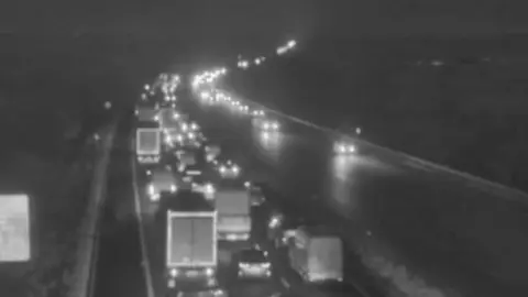black and white image from a motorway camera showing queuing traffic.