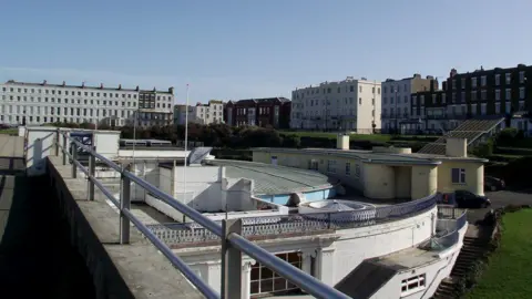Thanet District Council A view of the roof of the Margate Winter Gardens, a building of white portland stone with metal railings, on a sunny day.