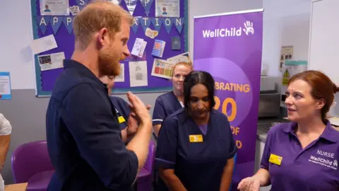 side view of prince harry as he talks to hospital staff 
