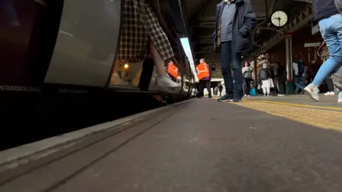 A passenger stepping off an East Midlands Railway train
