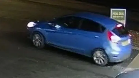 A blue Ford Fiesta driving on a motorway.