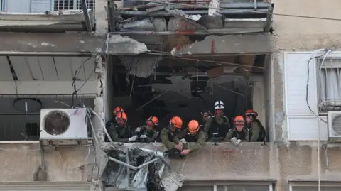 EPA Israeli Home Front Command personnel work at the scene after fragments from an intercepted Iranian ballistic missile hit in Tel Aviv, Israel, 15 March 2026