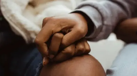 A close-up of two Black people's clasped hands.
