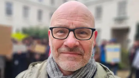 Heidi Booth/BBC Image of Paul. He has a bald head, grey stubble and is wearing black-framed glasses.