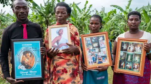 Four members of Monic's family including her mother hold up framed photos of Monic