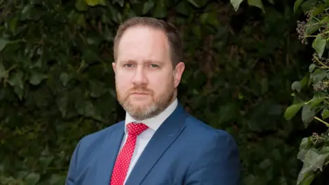 Leicestershire Police Federation A man with a beard in a blue suit with a red tie