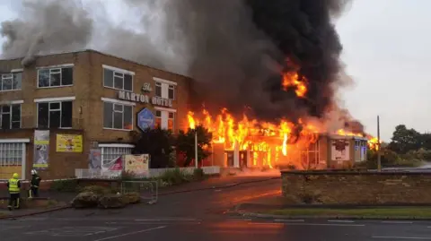 LDRS The two storey Marton Hotel and Country Club with flames rising from its windows and fire crews standing by