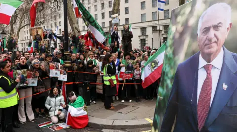A large image of Reza Pahlavi, the exiled son of Iran's last shah, is displayed as people gather on Saturday, in London, Britain. 