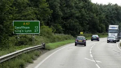 The A47 with cars on both carriageways and a road sign directing drivers to Swaffham and King's Lynn.