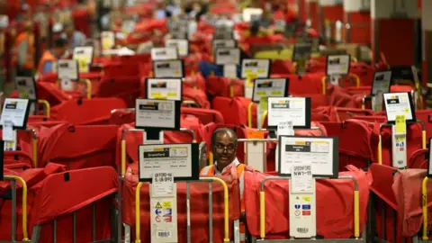 Getty Images An employee sorts deliveries at a Royal Mail centre in London during the Christmas period