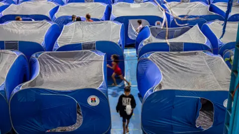 Getty Images Filipinos take shelter in tents inside a school gymnasium converted into an evacuation centre before Typhoon Goni hits on November 1, 2020 in Manila, Philippines