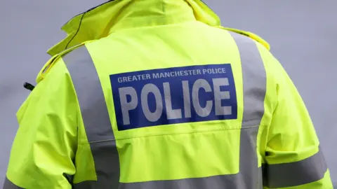 A high-vis police jacket with the words Greater Manchester Police on it. 