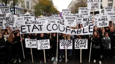 Reuters Protesters in Paris hold slogans that read: "The state is guilty". Photo: 23 November 2019