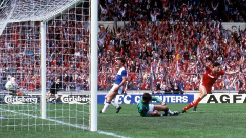 Ian Rush, in full red Liverpool kit, wheels away in celebration as he scores against Everton in the FA Cup Final