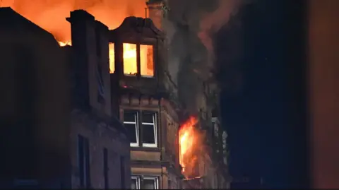 Stuart Cowper A fire at a block of flats in Perth. The flames are orange and coming out the top of the building.