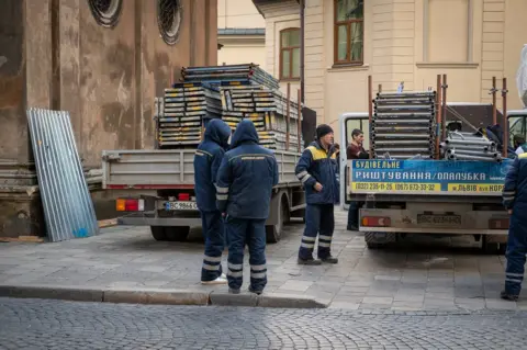 Scaffolders in Lviv's historic old town preparing to cover more of the city's stained glass windows.