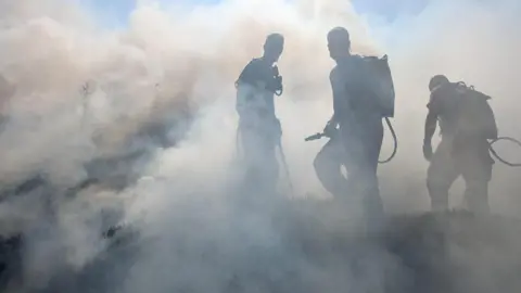 RSPB Scotland Three people with firefighting equipment in smoke during the firefighting effort earlier this month.