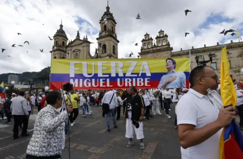 EPA People take part in the "March of Silence" in Bogota, Colombia, 15 June 2025. They are holding up a banner reading "Strength, Miguel Uribe" in the colours of the Colombian flag and adorned with a picture of the senator.  