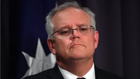 Getty Images Scott Morrison looks at the camera, with and Australian flag partially visible in the background