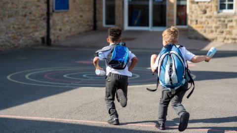 Children running through a playground to school