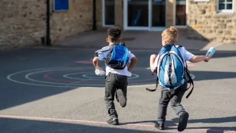 Getty Images Children running through a playground to school