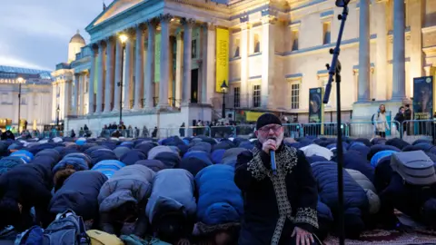 EPA/Shutterstock Members of the Muslim community pray ahead of the 'open iftar' Ramadan dinner event at Trafalgar Square in London
