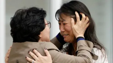 News1 Han Tae-soon reuniting with her daughter in 2019 at Seoul airport. Han is dressed in brown coat and crying as she hugs her daughter, who is wearing a white top.