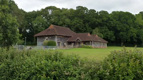 Google A Google Street image of the dark wood and red brick village hall.