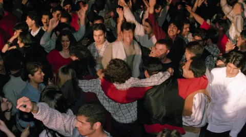 A crowd of young people, of South Asian heritage, dancing