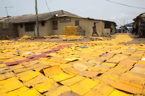 Nii Odzenma Yellow tapestry created by artist Serge Attukwei Clottey on a road in La - Accra, Ghana
