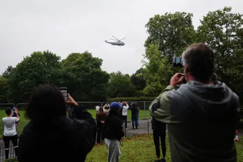 Jose Sarmento Matos/Bloomberg via Getty Images Bystanders take photographs as the Marine One helicopter departs from Winfield House, the US Ambassador's residence, in London
