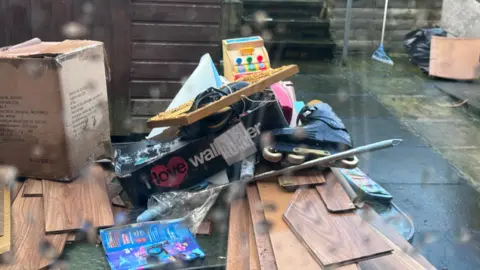 Piece of damaged flooring, wet cardboard boxes, a skate, toys and other items are piled in a heap outside a home in Kings Row, Coalisland