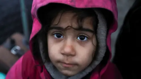 A child waits with other migrants at a transport and logistics centre near the Belarusian-Polish border