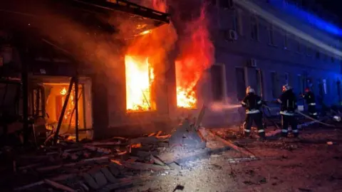 State Emergency Service of Ukraine/Reuters Firefighters tackle blaze which can be seen spewing out of a window. Rubble is on the floor nearby