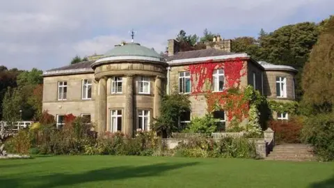 SUBMITTED An English country house type building set in a pretty garden setting. It has classical features including a dome and pillars at the front.