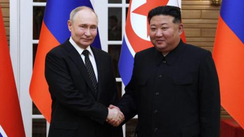 In this pool photograph distributed by the Russian state agency Sputnik, North Korea's leader Kim Jong Un (R) and and Russian President Vladimir Putin shake hands after a welcoming ceremony at Kim Il Sung Square in Pyongyang on June 19, 2024