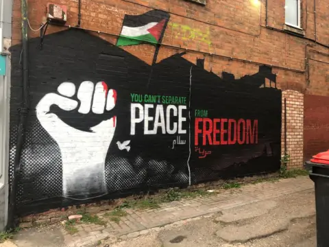 Elliot Ludvig A pro-Palestinian mural on a wall showing a white fist next to the painted slogan "you can't separate peace from freedom"