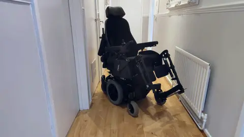 Dr Deborah Lawson Image of Dr Lawson's powered wheelchair in the narrow hall