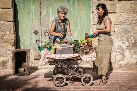 Joseph P Smith Woman bags some food for a customer at an outdoor stall