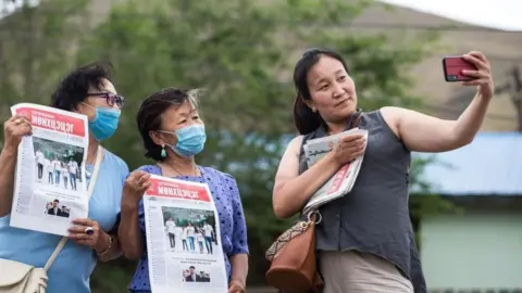 Supporters holding newspapers as they pose for a selfie during a campaign event for the Mongolian People's Party in Ulaanbaatar, June 2020