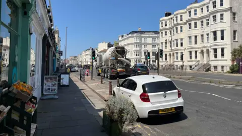 The A259 in hove which has a parade of independent shops with fruit and signage outside. There are currently two lanes which would go down to one lane