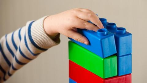 Child's hand reaching for toy bricks