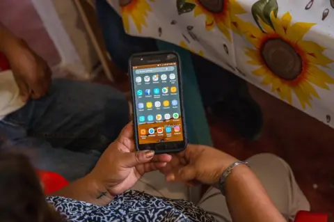 Brett Gundlock Maria del Rosario Rodriguez, holds her son's Ricardo Flores' cell phone, in their family's home in Acatlán, Puebla, Mexico, October 18, 2018