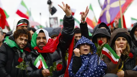 AFP via Getty Images A crowd of of people pictured waving flags and making peace signs with their hands