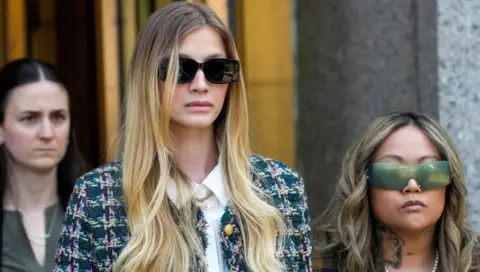 Cassie Ventura's friend Bryana Bongolan, leaves the Federal court. She has long blonde hair and is wearing a tweed suit coat, white shirt and sunglasses
