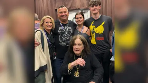Louis Osbourne Pictured is Louis Osbourne with his wife, two children and Ozzy sat down in front of them while they gather around him smiling